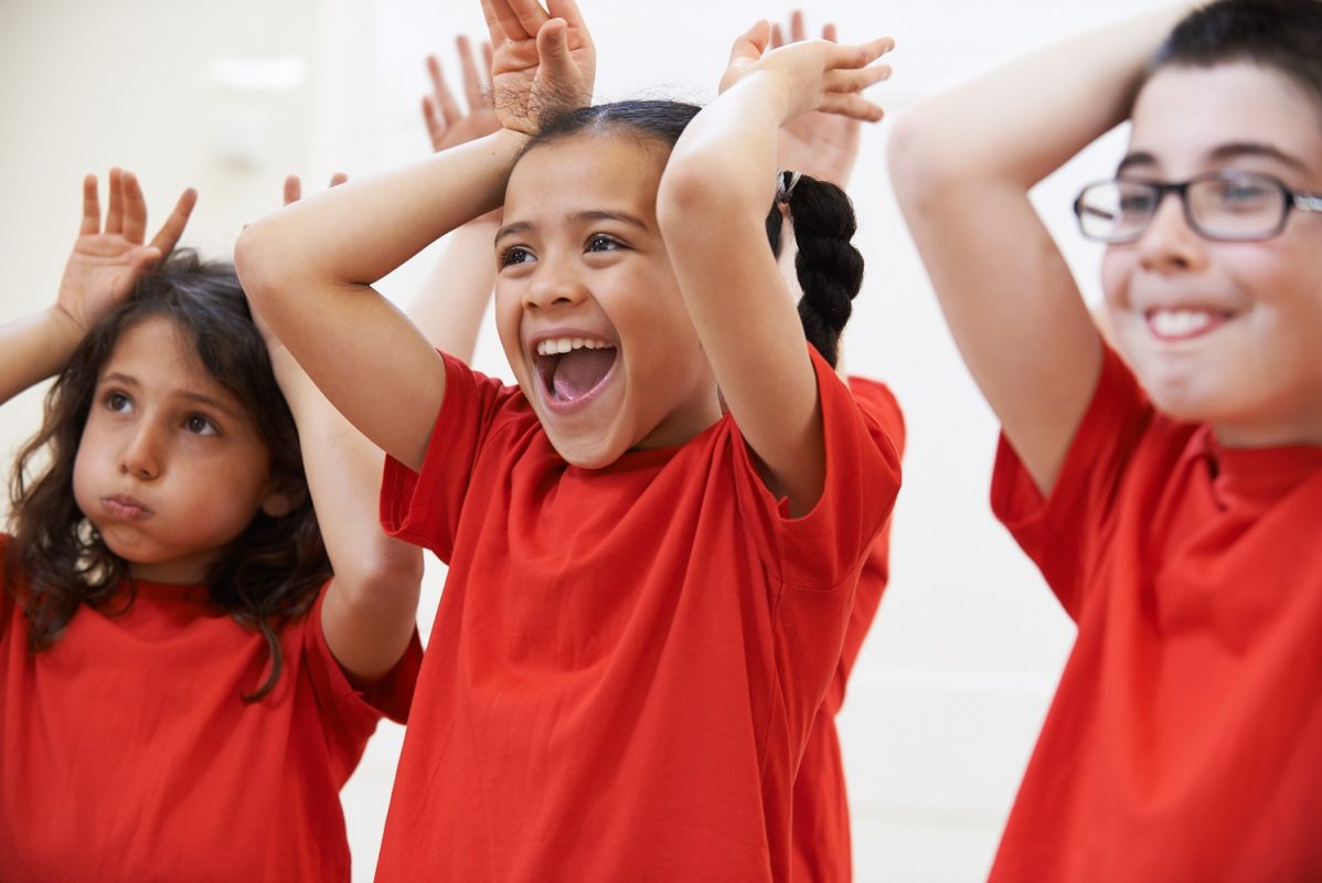 three children taking part in a music class putting their hands up like bunny ears