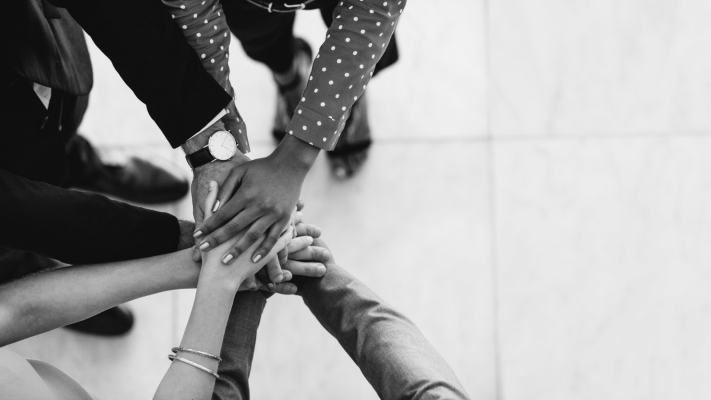 A birds eye view of business colleagues high-fiving, representing the supportive nature of corporate impact.