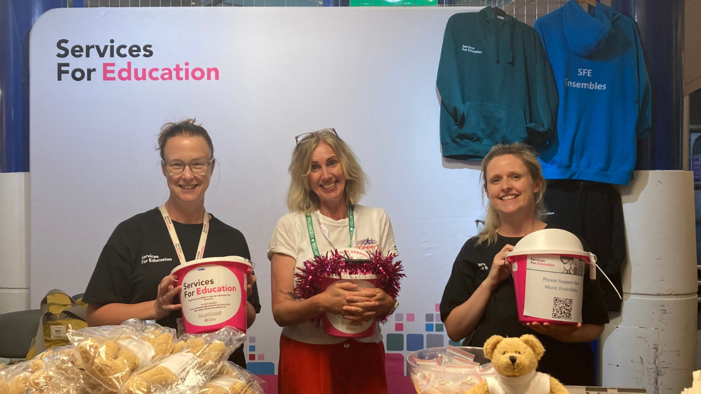 A photograph of SFE employees and volunteers holding pink fundraising buckets at Services For Education's Youth Proms.