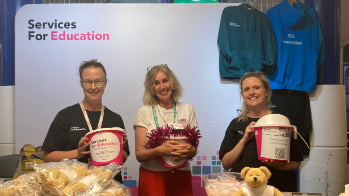 A photograph of SFE employees and volunteers holding pink fundraising buckets at Services For Education's Youth Proms.